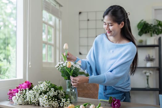 A woman enjoys arranging fresh flowers in a sunny room showcasing her creativity and love for floral design.