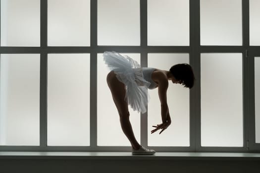 Brunette in tutu and sneakers leaning forward staying on window sill profile shot