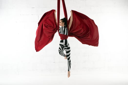 Slim gymnast in striped body exercising on cloth view against brick wall