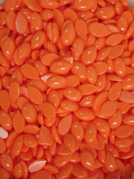 Background orange wax in depilatory granules close-up, vertical