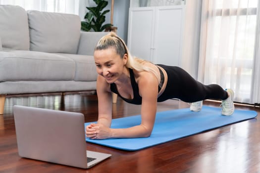 Athletic and sporty senior woman planking on fitness exercising mat while watching online fitness video at home exercise as concept of healthy fit body lifestyle after retirement. Clout