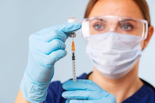 Doctor in gloves fills a syringe with medicine from vial, close-up. Vaccination and immunization