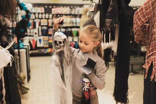 Girl chooses a skeleton toy in a store for halloween