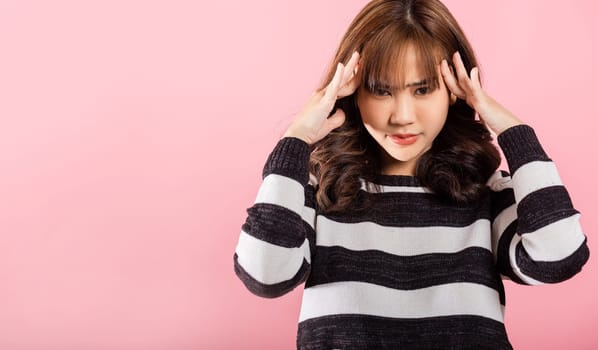 Portrait of beautiful Asian young woman sad tired strain face holding hold head by hands, stress female person unhappy closed eyes problem she headache, studio shot isolated on pink background