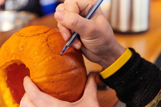 A modern blonde woman in military uniform is carving spooky pumpkins with a knife for Halloween night.