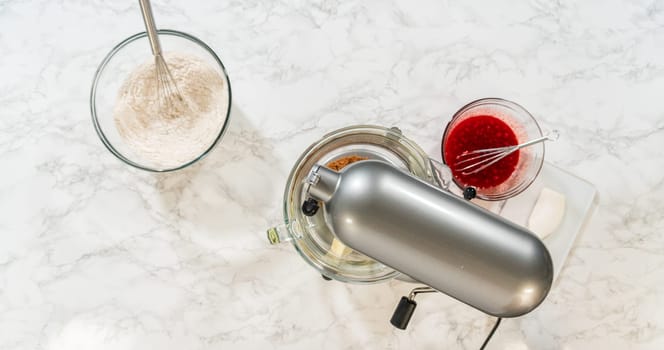 A baking setup with a stand mixer, flour with spices, softened butter, and molasses mixture, all set up to create the Classic Red Gingerbread Dough. Each ingredient is prepared and ready for mixing.