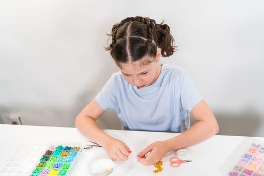 Little girl enjoys crafting colorful bracelets with vibrant clay beads set.