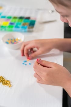 Little girl enjoys crafting colorful bracelets with vibrant clay beads set.