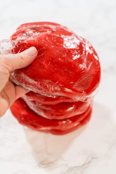 Four portions of the Classic Red Gingerbread Dough, each wrapped in plastic, are stacked and ready for refrigeration. This step allows the dough to rest and develop flavor before baking.