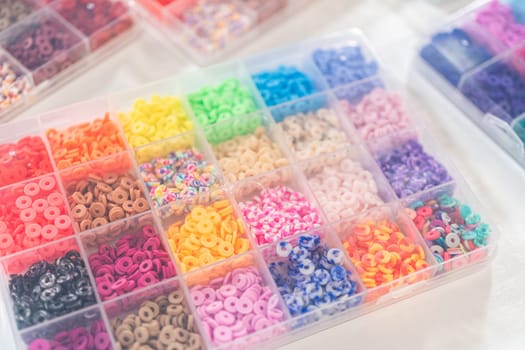 Assorted clay bead boxes neatly arranged on a white table, awaiting a creative kids' craft project.