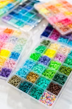 Assorted clay bead boxes neatly arranged on a white table, awaiting a creative kids' craft project.