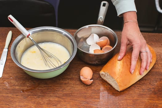 In a bowl there is a mixture for making an omelet and on the shells for eggs and a loaf. Prepare breakfast.