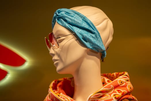 The face of a female mannequin in sunglasses behind the glass of a display case.