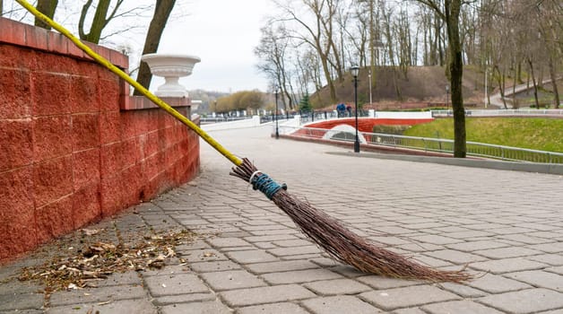Retro broom made of dry branches against the backdrop of a city park.