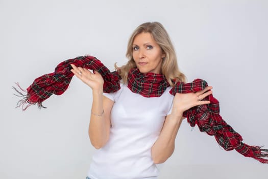 A beautiful adult woman waves a checkered warm scarf.
