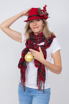 A beautiful adult woman in a Christmas red hat holds a golden fir ball.
