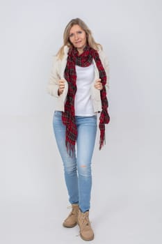 Full length beautiful adult woman wearing blue jeans and a warm sweater on a gray background.