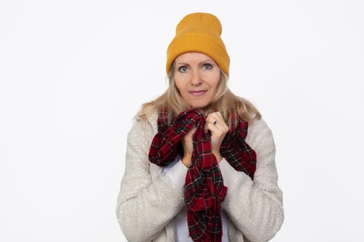 A beautiful adult woman in a knitted hat and scarf smiles and looks at the camera.