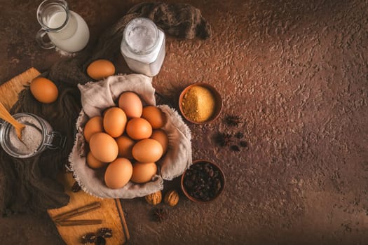 Organic brown eggs with assorted baking ingredients and kitchen utensils in brown tone