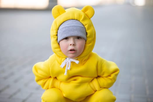 Funny little girl in a warm yellow suit with ears on a walk.