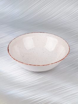 White empty deep clay plate with a spoon on a gray background.