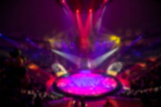 Blurred circus arena in light rays and multi-colored lights.