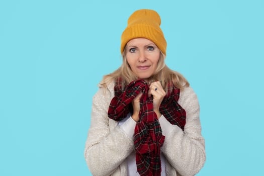 Adult beautiful woman in warm winter clothes on a blue background.