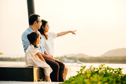 A family sitting on a bench pointing at something