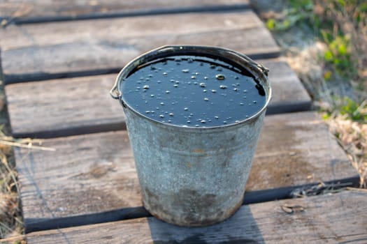 Used car motor oil in a metal bucket.