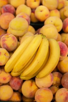 Branch of yellow ripe bananas and peaches.Tropical fruits on sale.