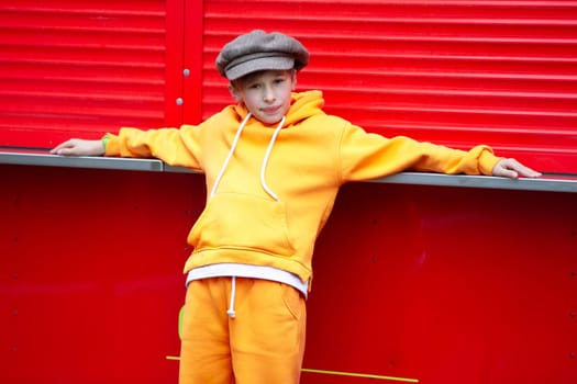 Happy boy in a vintage hat and orange suit posing at a red kiosk.