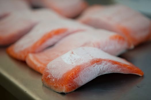 Frozen pieces of red salmon fish on a metal table.