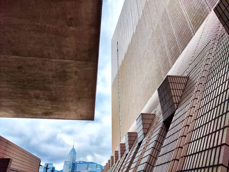 A close-up view of brick-patterned building facade with an overhanging concrete structure in Hong Kong, showcasing a unique architectural design