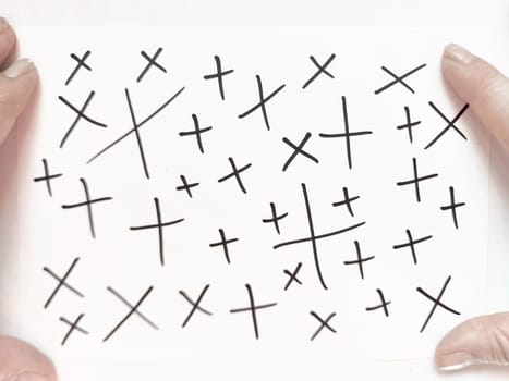 Someone is displaying a card filled with a random pattern of plus and cross symbols, emphasizing a creative expression.