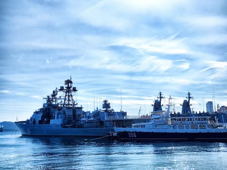 Vladivostok, Russia - October 07, 2023: Multiple naval vessels are docked at a bustling port under bright blue skies