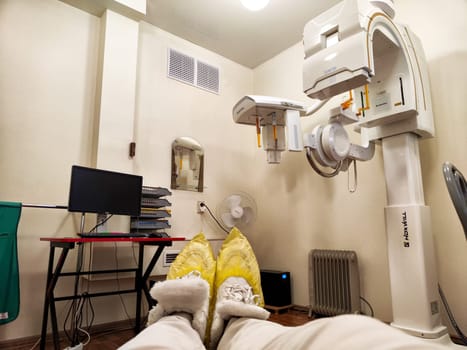 Kirov, Russia - November 28, 2024: In a hospital's X-ray room, a patient is seated, ready for their imaging procedure while medical equipment is positioned nearby.