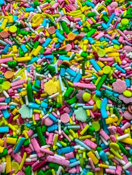 Multicolored small candies of different shapes. Top view. Bright children's background