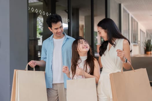 Happy family on a holiday shopping trip, parents and children smiling and carrying shopping bags.
