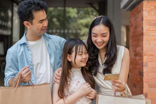 A happy family enjoys a shopping spree, using a credit card for purchases, showcasing modern retail convenience and family bonding.