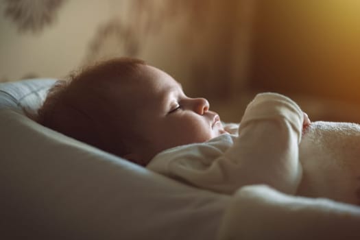 Cute baby in white clothes sleeping in bed. Adorable kid portrait. 3-4 month old child. Babyhood and parenting concept. High quality photo
