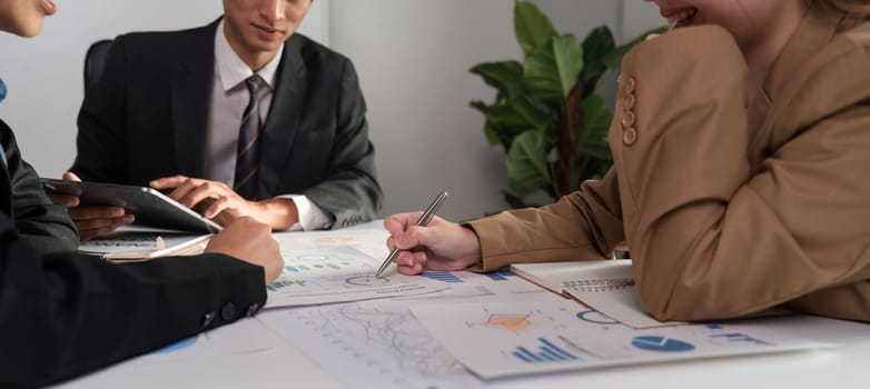 A diverse team of business professionals engaged in analyzing graphs and charts during a collaborative meeting.