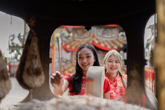 Two young women celebrate Chinese New Year joyfully engaging in traditional activities in a vibrant cultural setting.