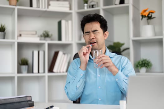A sick man takes medicine with a glass of water emphasizing the importance of self-care and wellness.