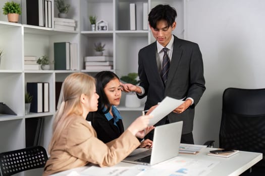 Professional business team engaged in discussion and analysis of work plans in a contemporary office environment.