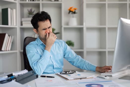 A sick employee feels overwhelmed and stressed at his desk highlighting the challenges of work-life balance.