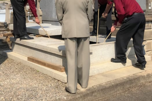 Porters lower the coffin into the grave in the cemetery