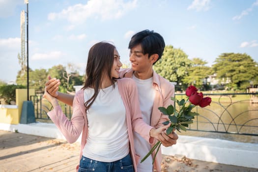 A couple shares a tender moment with roses in a park celebrating their love on Valentine's Day.