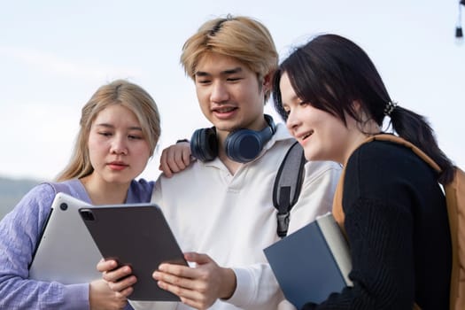 Students collaborate on digital devices outside, enhancing their learning experience in a modern, tech-savvy environment.