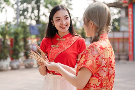 Two friends celebrate Chinese New Year sharing smiles and traditions in a vibrant outdoor environment.