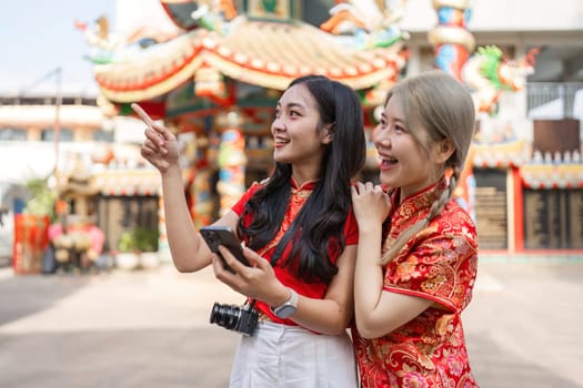 Two friends celebrate Chinese New Year at a shrine capturing joyful moments filled with worship and cultural appreciation.